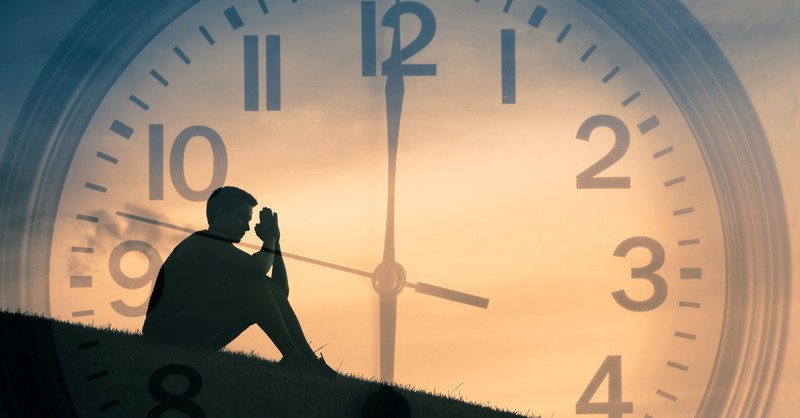 Man praying in front of the clock