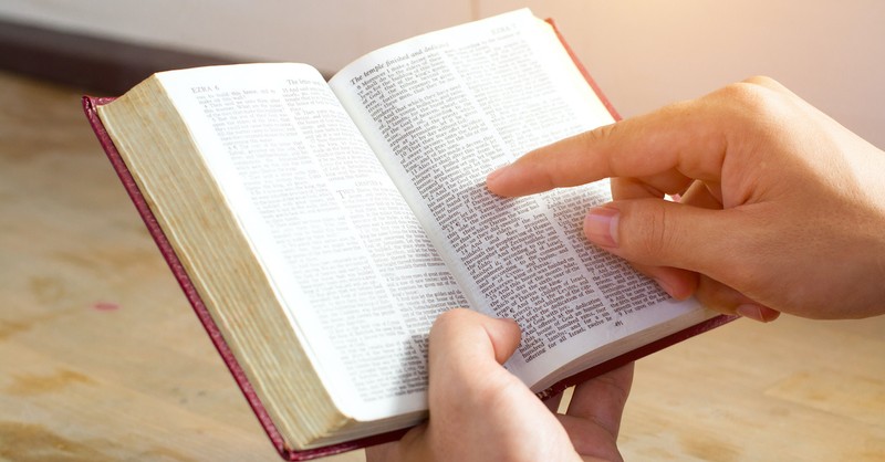 hand pointing in open Bible