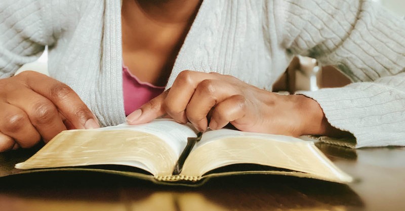 woman reading Bible and pointing to page