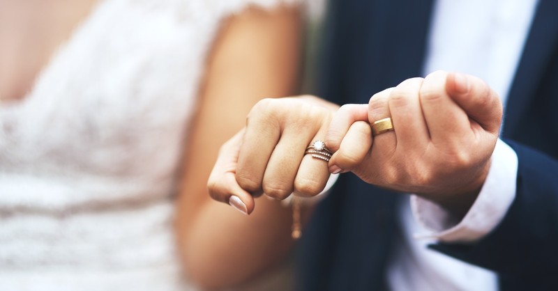 Groom and Bride pinkies linked with wedding rings