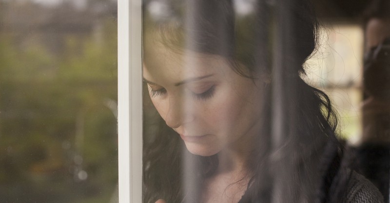 sad woman looking down behind window