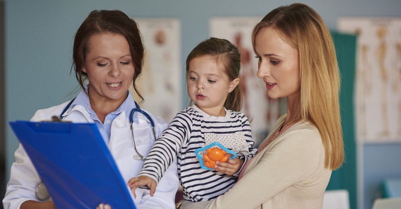 pediatrician showing clipboard to mom and young daughter