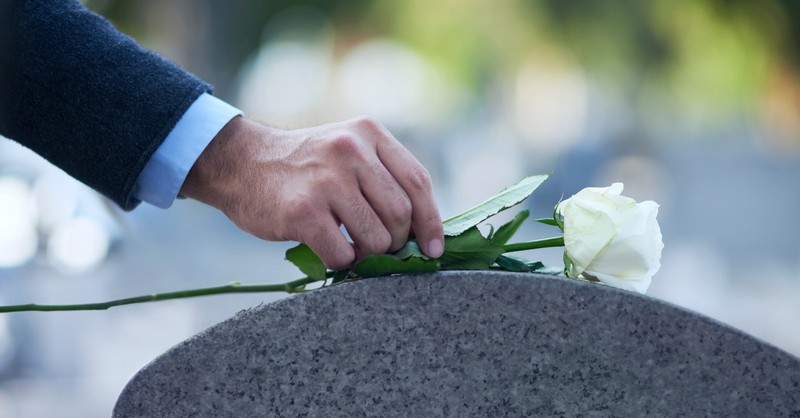 Placing a rose on a grave stone
