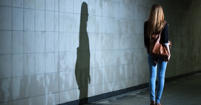 woman and her shadow walking beside wall