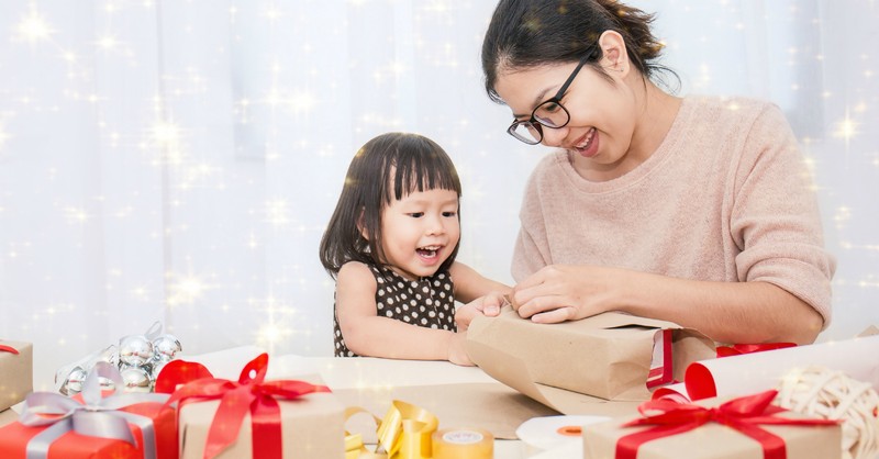 Mom and toddler wrapping Christmas gifts together