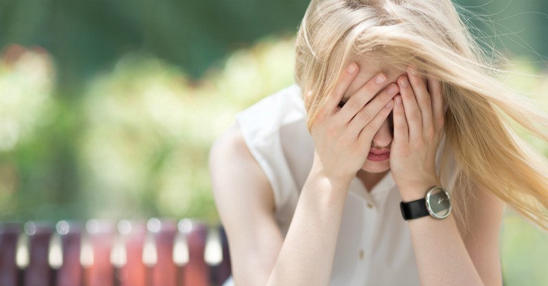 woman sitting on bench with face in hands, sin of pride