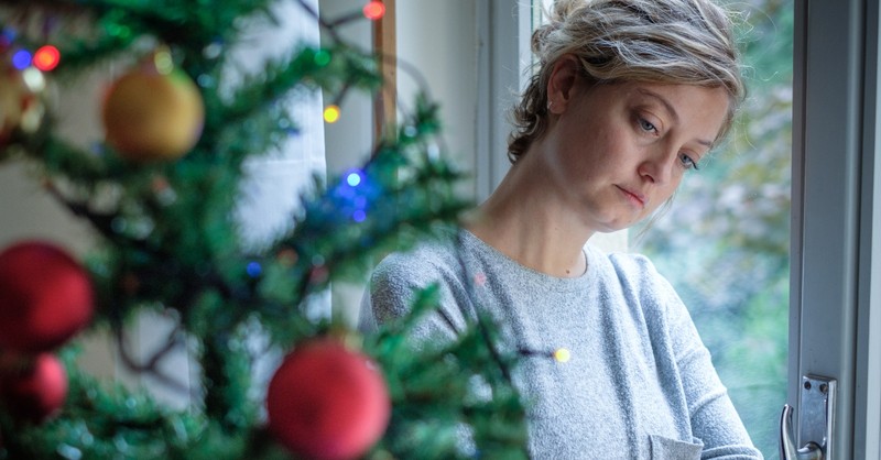 sad woman standing by Christmas tree