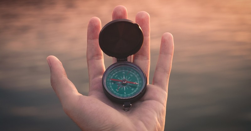 Person holding a compass in their open hand