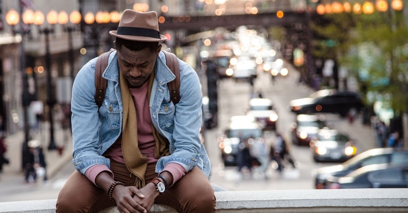 Sad, worried man sitting on a wall to illustrate david grieving for absalom