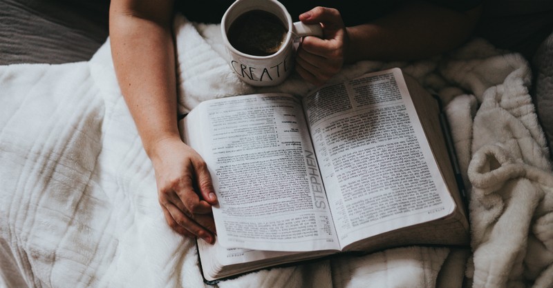 man reading Bible while drinking coffee