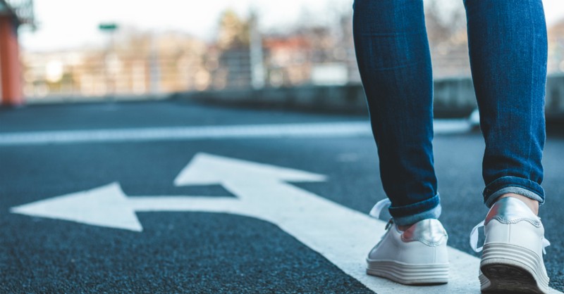 feet walking on street with arrow pointing