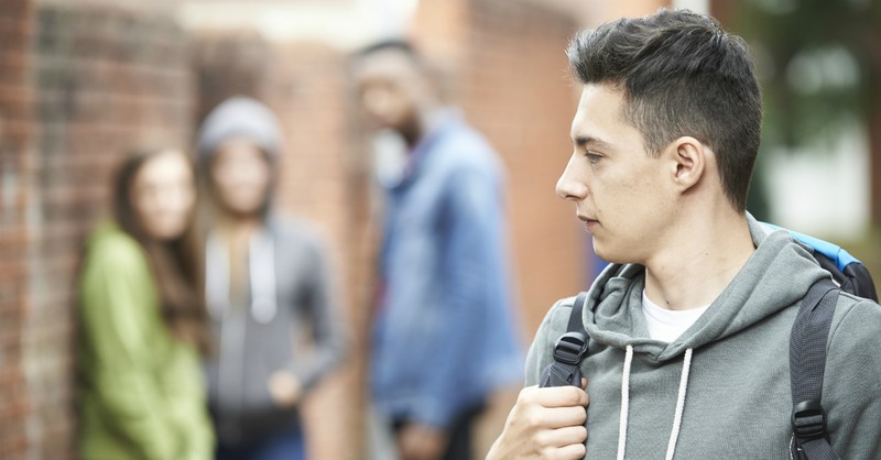 teen looking at group standing apart from them