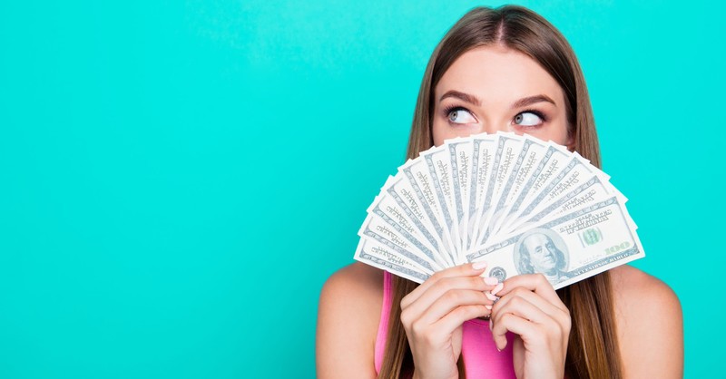 woman fanning dollar bills in front of her face