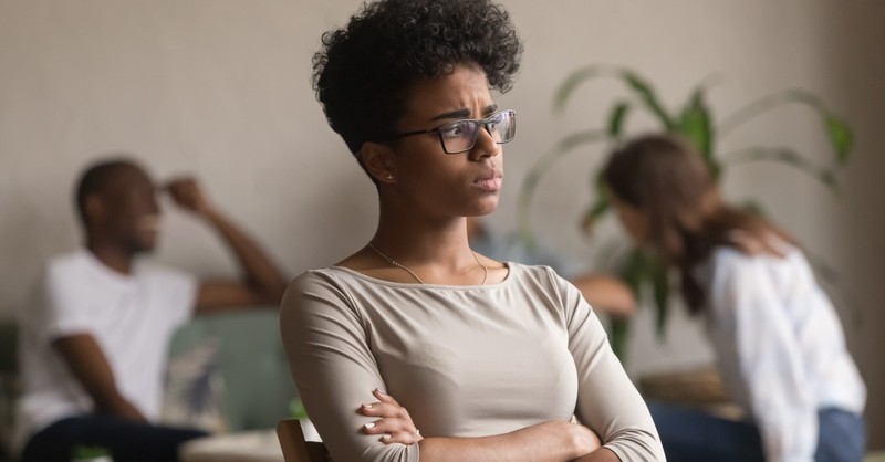 woman standing away from friends looking worried or confused