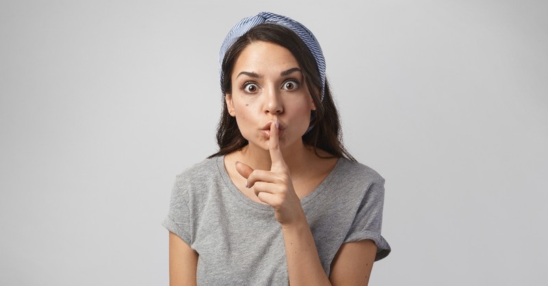 Woman holding a finger over her mouth to be quiet