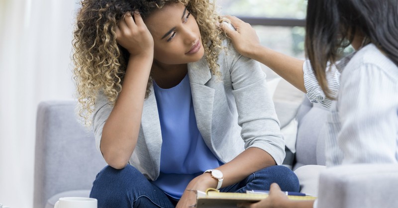 woman looking downcast being counseled by another woman