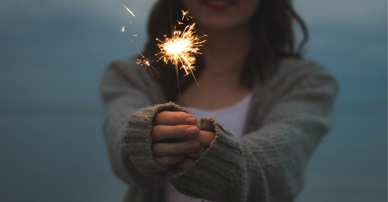 girl holding sparkler in dark outdoor setting