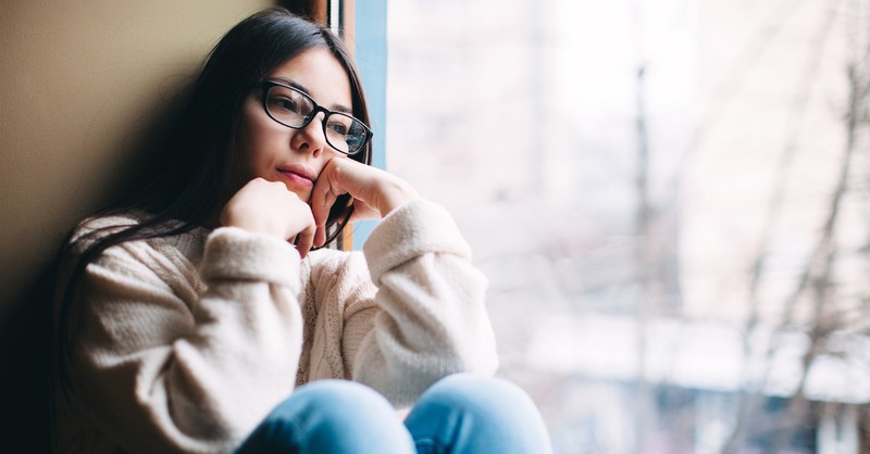 woman looking sad or bored staring out window