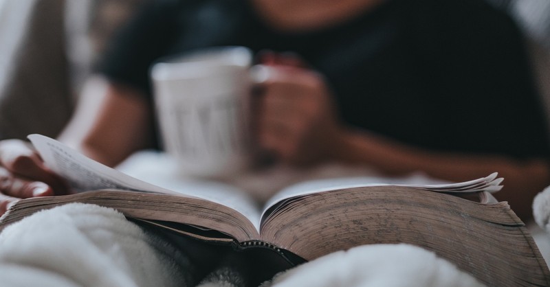 Person sitting with a cup of coffee and an open Bible