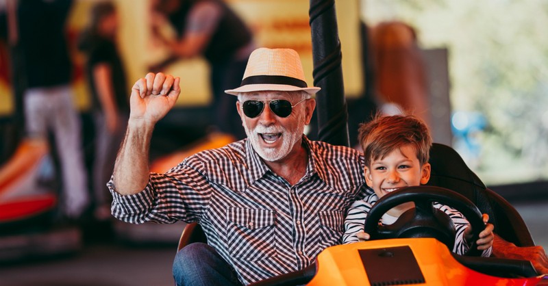 grandfather and grandson riding in bumper cars looking happy