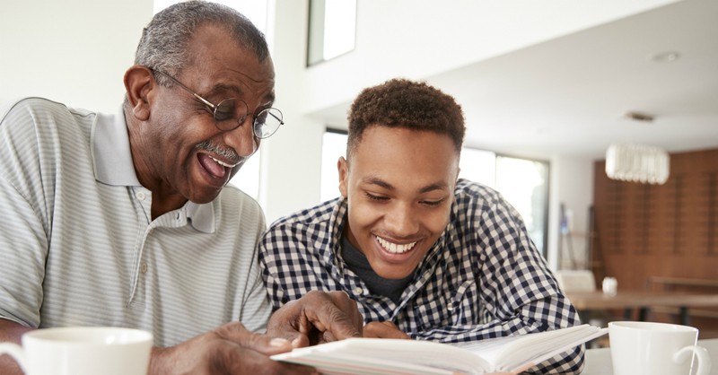 grandfather and grandson reading and laughing together