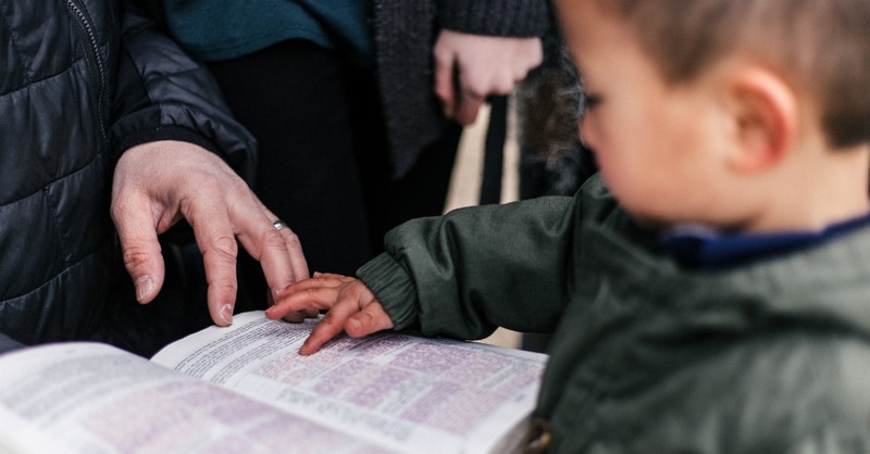 child reading Bible with parents