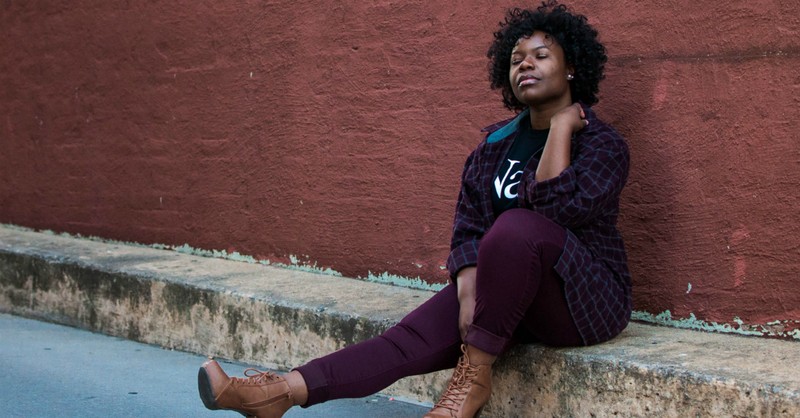 woman sitting on sidewalk looking peaceful with eyes closed