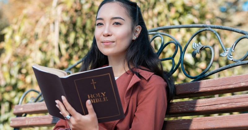 young woman reading bible looking peaceful and thoughtful