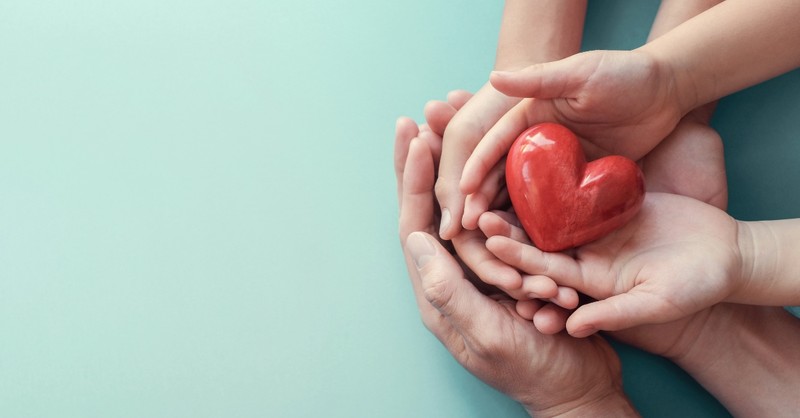 Three sets of hands holding a small heart