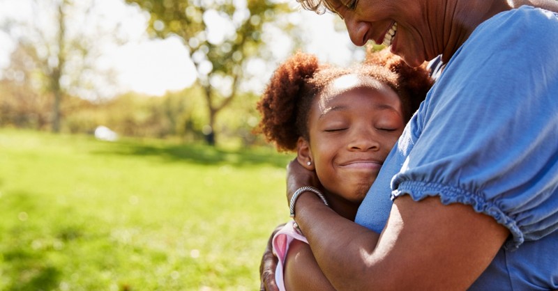 grandmother hugging granddaughter on sunny day outdoors