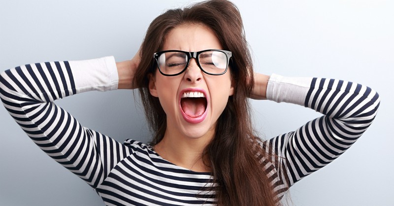 woman holding head screaming in frustration