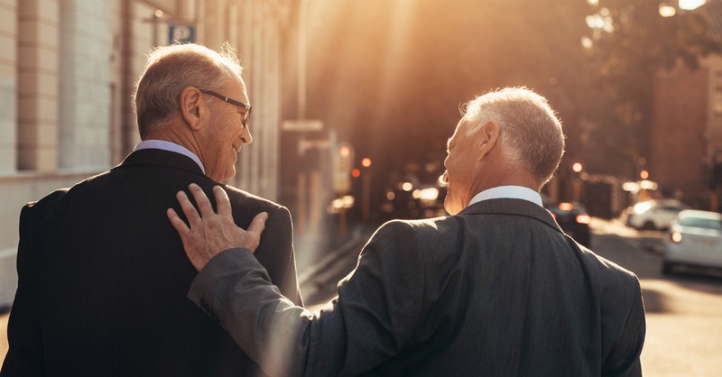 two men walking in suits sharing encouragement