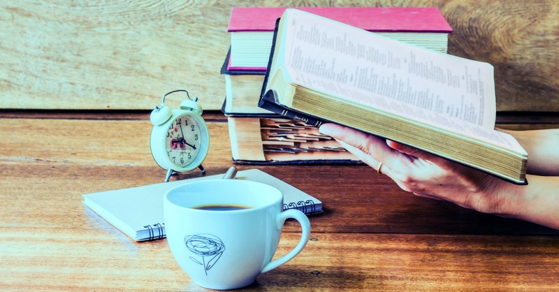 alarm clock coffee cup and open Bible on table