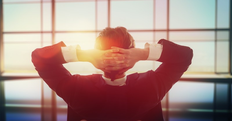 man resting hands behind his head, looking at the sunset