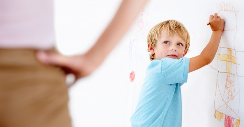 child drawing on the wall with crayons