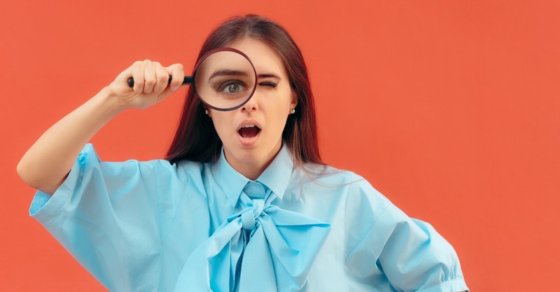 woman looking shocked through a magnifying glass