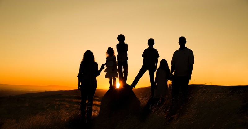 family standing together at sunset