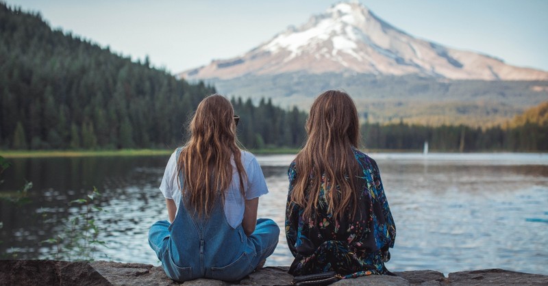 Two women sitting by a lake