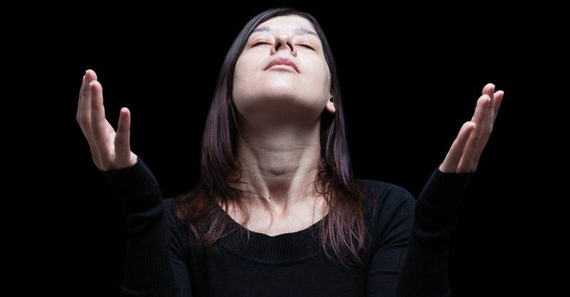 woman in black backdrop lifting her hands in praise