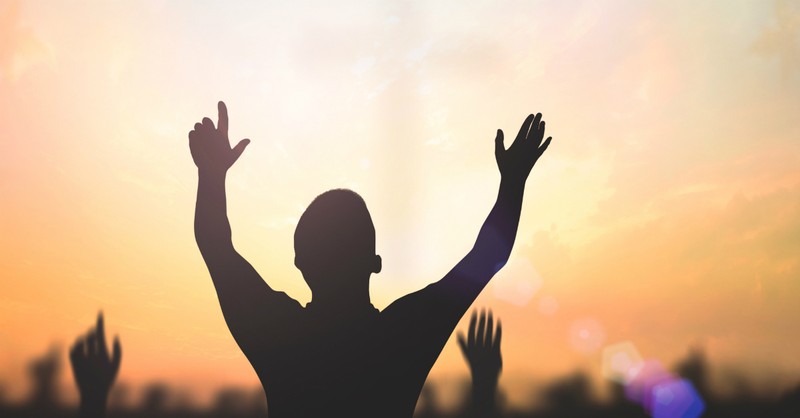 man lifting his hands in praise; resurrecting into a new body through Christ