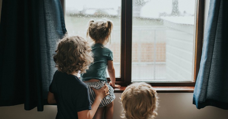 mom with children looking out rainy window