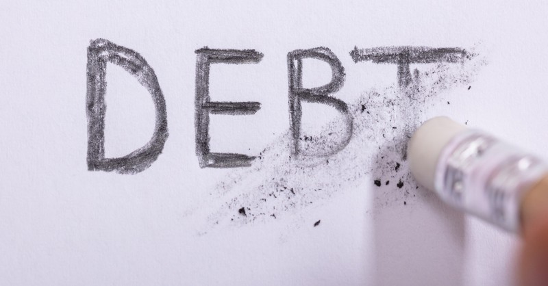 An eraser erasing the word "DEBT" written in pencil