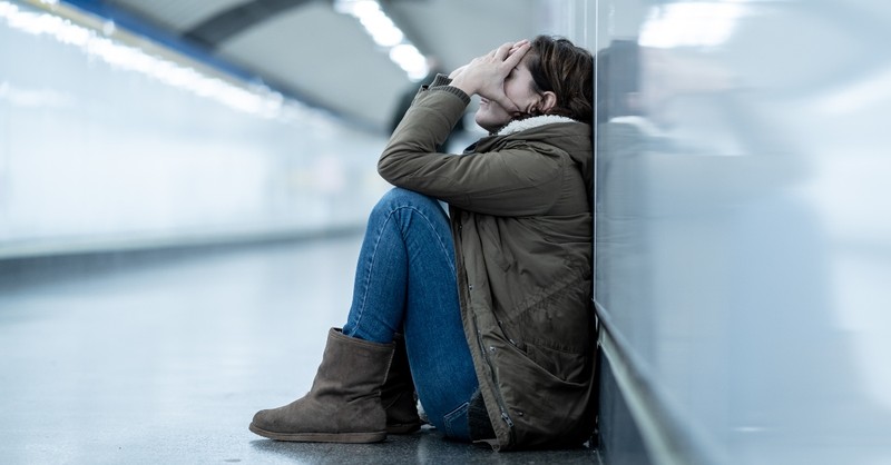 anxious and scared woman sitting on ground of metro