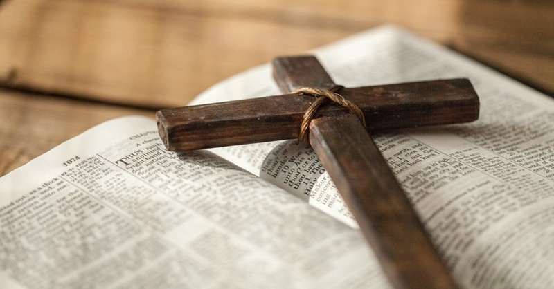 Wooden cross sitting atop an open Bible