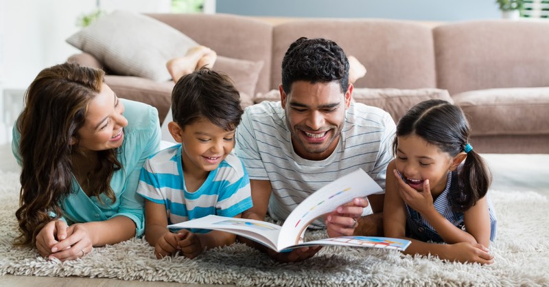 family looking at book on floor in living room