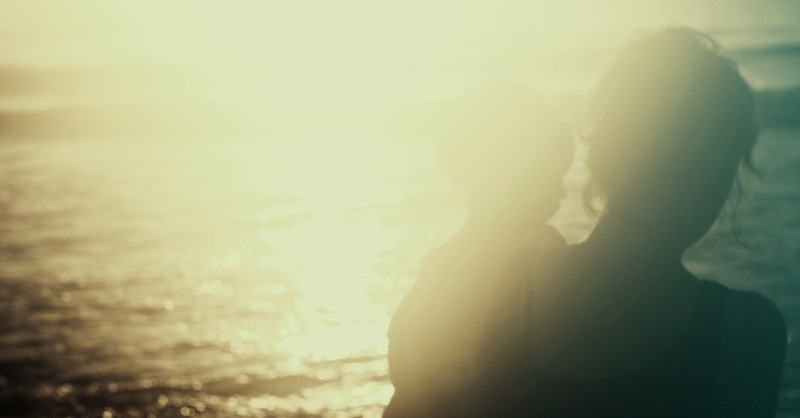 blurry image of mother holding child looking at ocean
