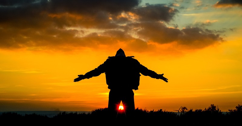 man on knees in praise at sunset with arms out wide