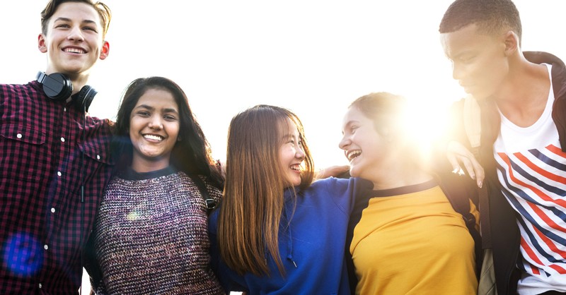 friends embracing one another with the sunshine in the background