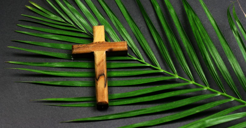 wooden cross on top of palm leave, hosanna said at palm sunday