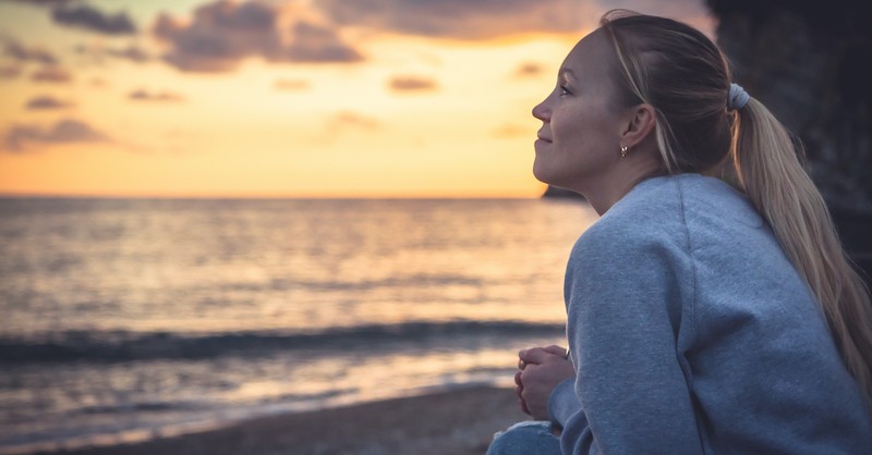 woman looking content at sunset over ocean